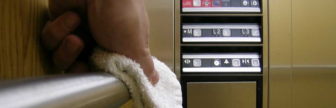hand cleaning railing inside elevator